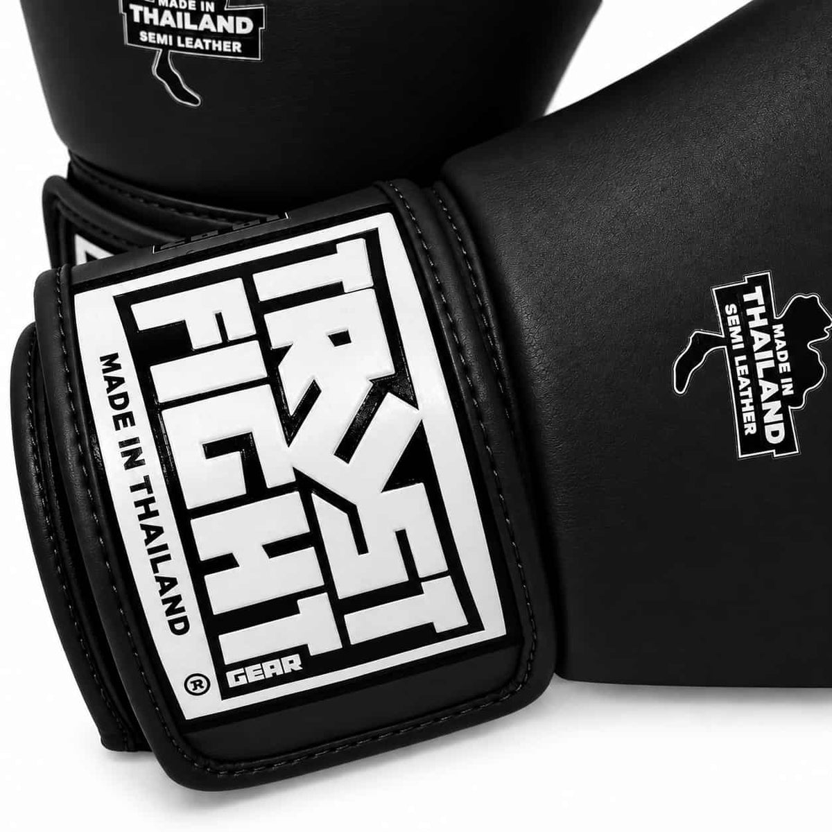 Luvas TRUST pretas para kickboxing, vista da marca. Fabricadas na Tailândia.
