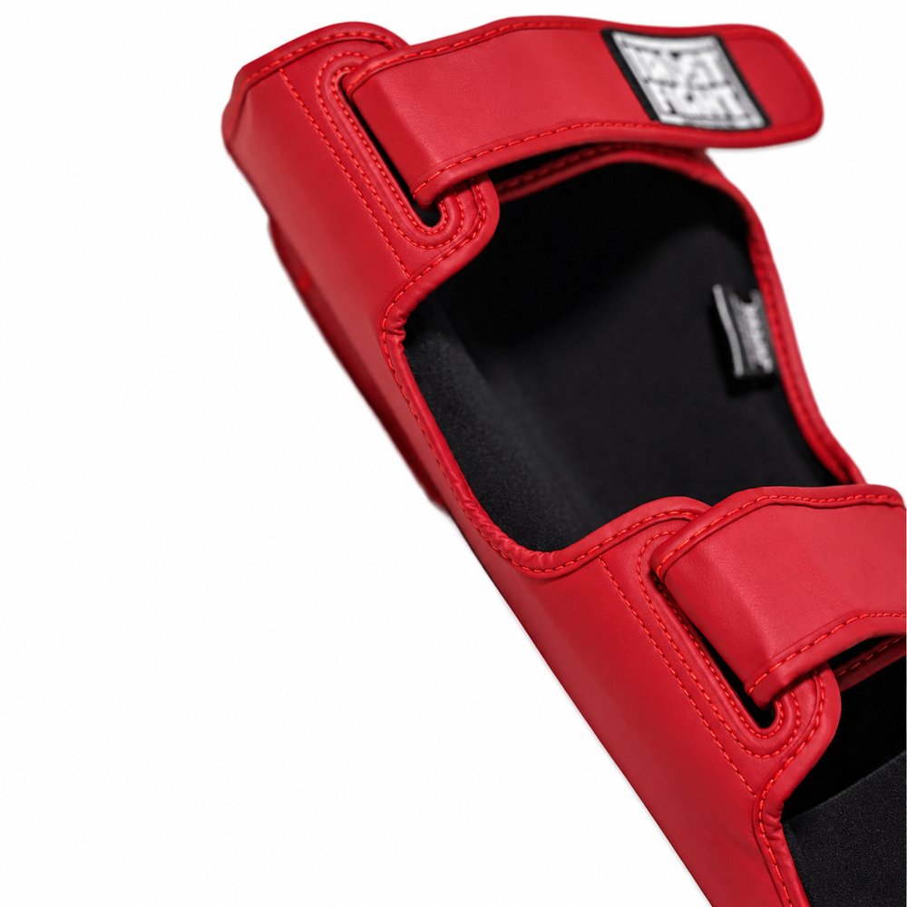 Detalhe das caneleiras TRUST vermelhas com interior preto, fechos de velcro e costuras vermelhas